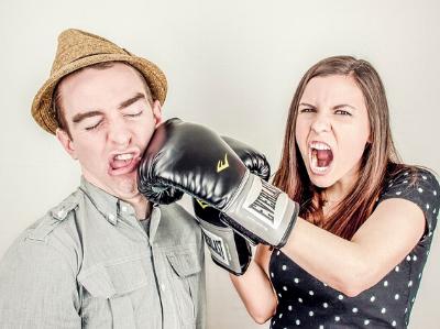 Frau mit Boxhandschuh schlägt Mann