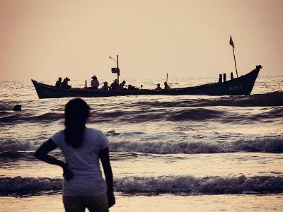 Mädchen am Strand beobachtet das Ablegen eines Flüchtlingsbootes