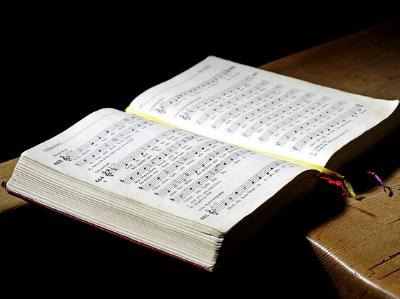 aufgeschlagenes Gesangbuch auf einer Holzbank
