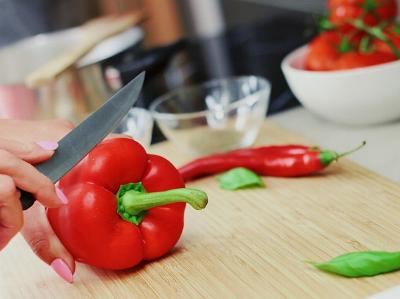 Szene beim Kochen: Frau schneidet Paprika 