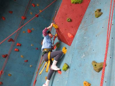 Jugendlicher klettert an einer künstlichen Kletterwand nach oben