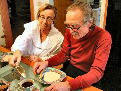 Mann und Frau am Tisch, sie schüttet ihm Milch in den Kaffee