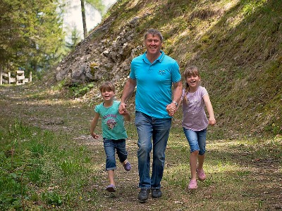 Vater mit zwei Töchtern rennen auf Waldweg