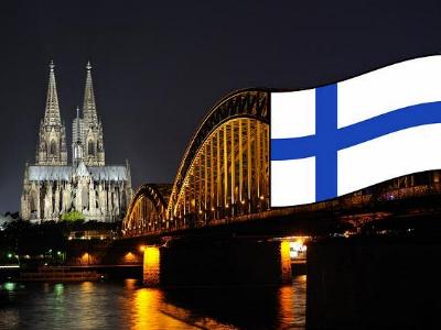 Kölner Dom und Deutzer Brücke bei Nacht mit finnischer Fahne