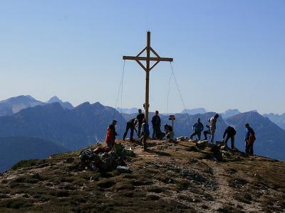 Menschen auf einem Berg, um ein Gipfelkreuz versammelt