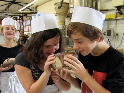 Zwei Jugendliche schnuppern an einem Laib Brot
