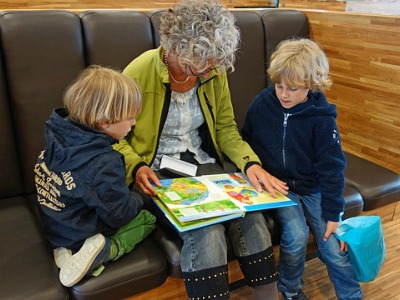 Frau und zwei Kinder lesen gemeinsam ein Buch