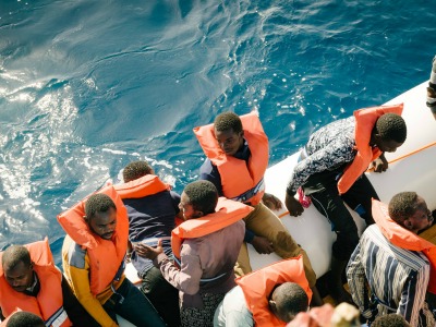 Blick von oben auf Flüchtlinge mit Schwimmwesten in einem Schlauchboot