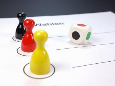 Spielfiguren in schwarz, rot und gelb auf einem Wahlzettel