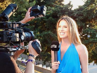 junge Reporterin mit Mikrofon steht vor Kameras