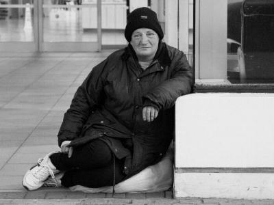 obdachlose Frau sitzt auf dem Boden