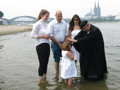 evangelischer Pfarrer tauft Kind im Rhein