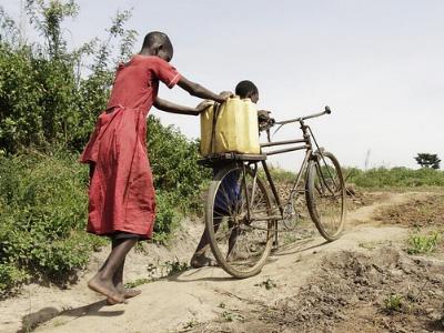zwei afrikanische Kinder mit Fahrrad und Wasserkanister