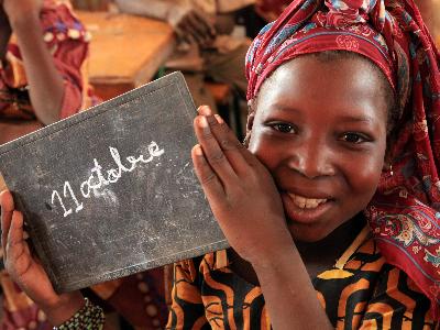 Ein afrikanisches Mädchen hält eine Tafel mit der Aufschrift '11. Oktober'