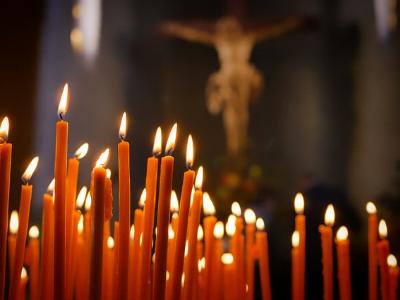 In einer Kirche: brennende Kerzen vor einem Kruzifix