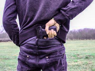 Mann zieht Pistole aus dem Hosenbund