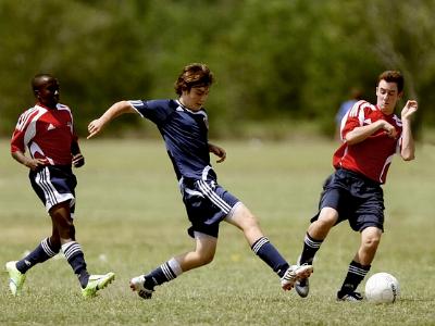 drei junge Fußballer im Kampf um den Ball