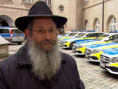 jüdischer Rabbiner vor einer Reihe von deutschen Polizeifahrzeugen