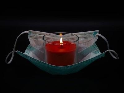 brennende Kerze steht auf einem medizinischen Mundschutz
