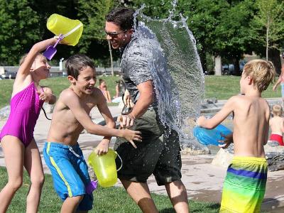 Kinder verfolgen einen Erwachsenen bei einer Wasserschlacht