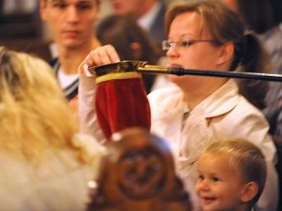 Frau wirft im Gottesdienst Geld in den Kollektenbeutel