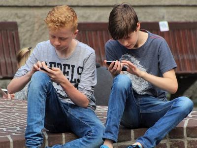 zwei Jugendliche sind mit ihren Handys beschäftigt
