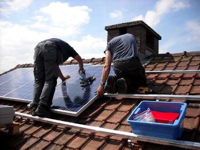 zwei Arbeiter installieren eine Solaranlage auf dem Dach