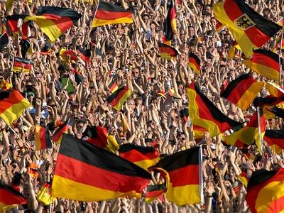 Fußballfans auf der Tribüne schwenken deutsche Flaggen
