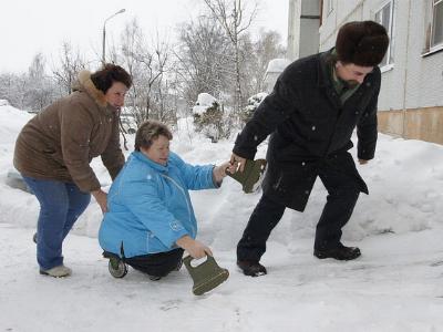 zwei Helfer ziehen eine beinamputierte Frau durch den Schnee