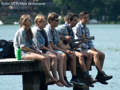 Pfadfinder sitzen auf einem Steg am See