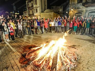 junge Mneschen stehen um ein großes Lagerfeuer