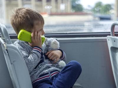 kleiner Junge mit Teddy telefoniert im Bus