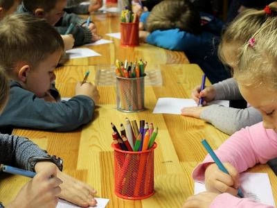 Kinder sitzen am Tisch und malen