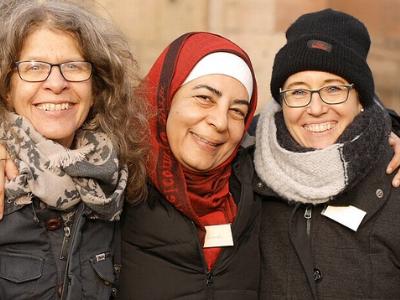 drei Frauen aus verschiedenen Ländern lächeln in die Kamera