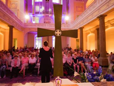 Foto: Bonner Kirchennacht | Meike Boeschmeyer im Vordergrund ein großes Kreuz, dahinter versammelte Gemeinde